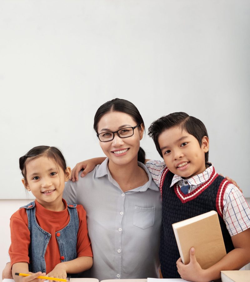 Happy kids and their smiling teacher in class